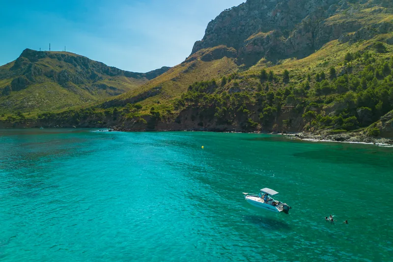 Cala de aguas transparentes con la lancha fondeada
