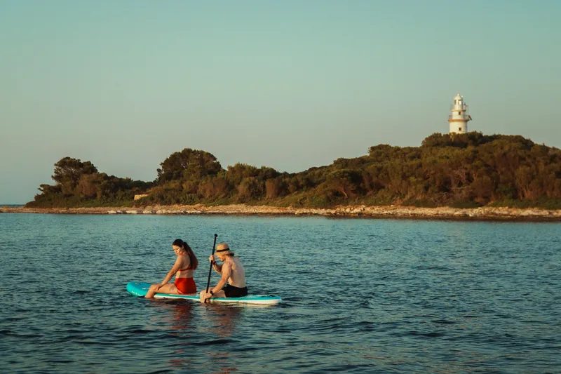 Paddle surf con el faro de Alcanada al fondo